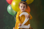 Kleinkind mit Luftballons hält Zahl Zwei 